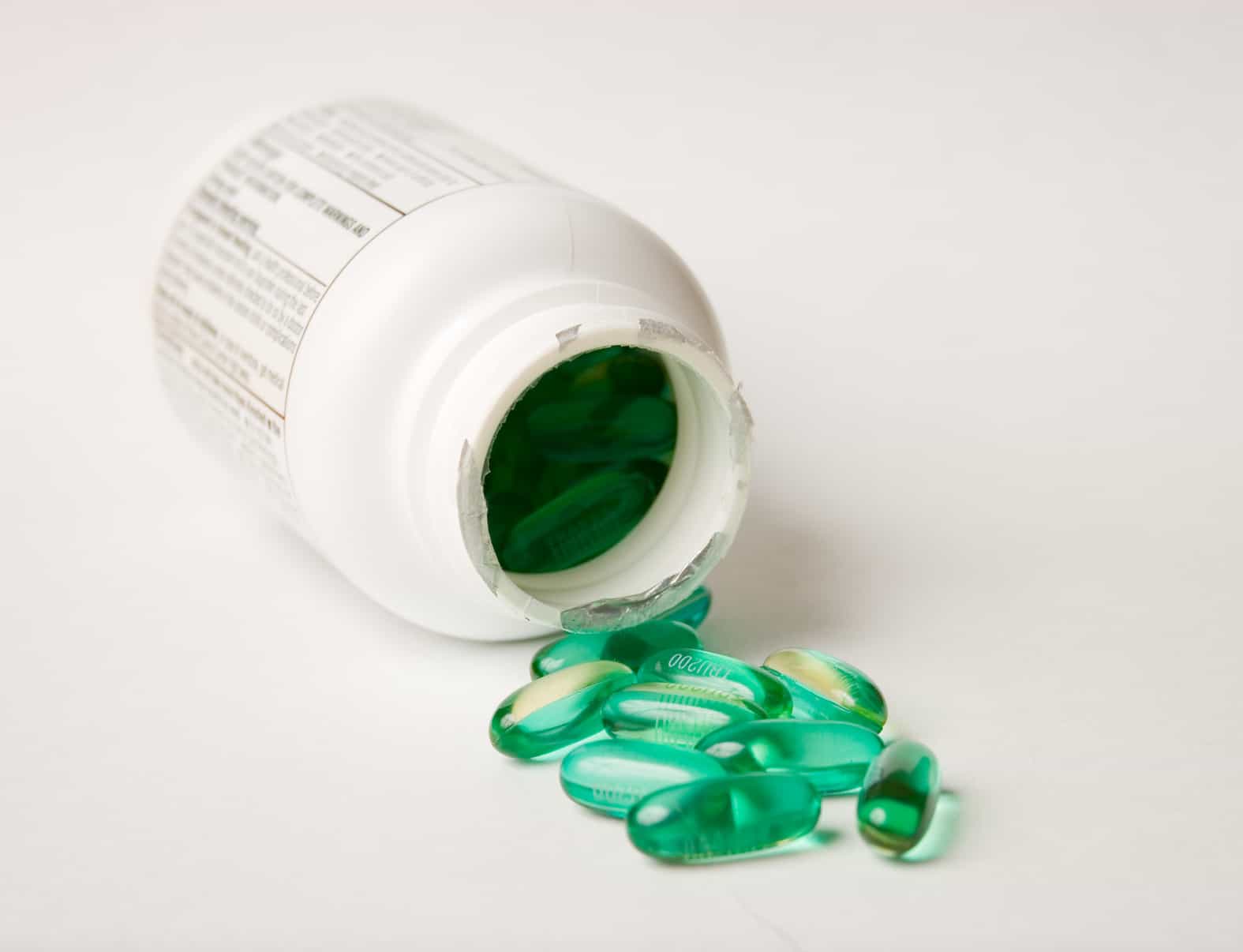 Green pills spilling from medicine bottle.