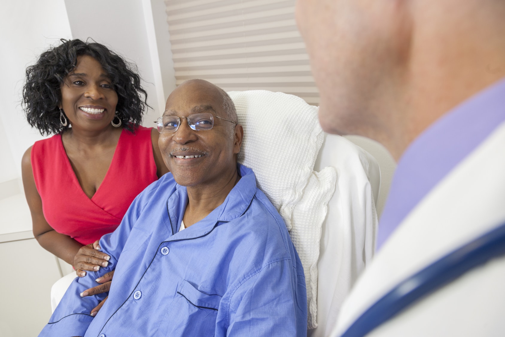 Older African-American couple speaking with doctor.