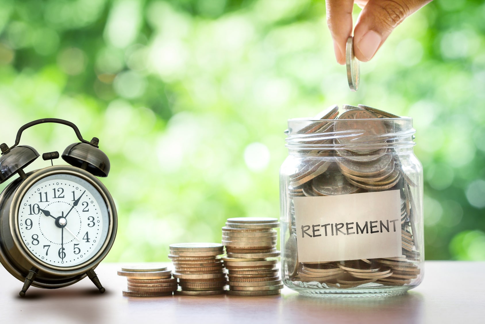 Alarm clock next to glass jar filled with coins labeled "retirement."