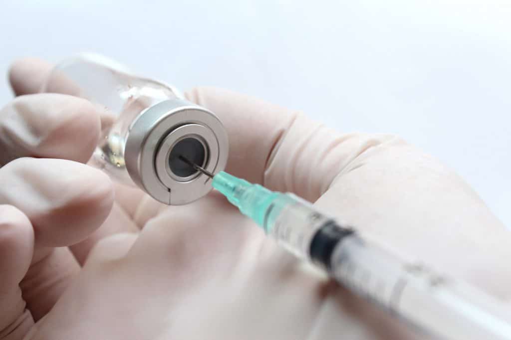 Scientist drawing vaccine from a vial.