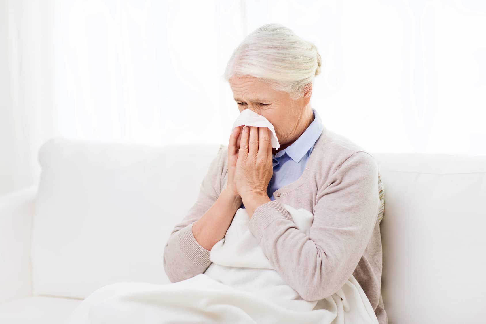 Elderly woman blowing her nose.