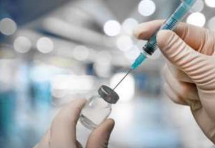 Scientist withdrawing vaccine from a vial.