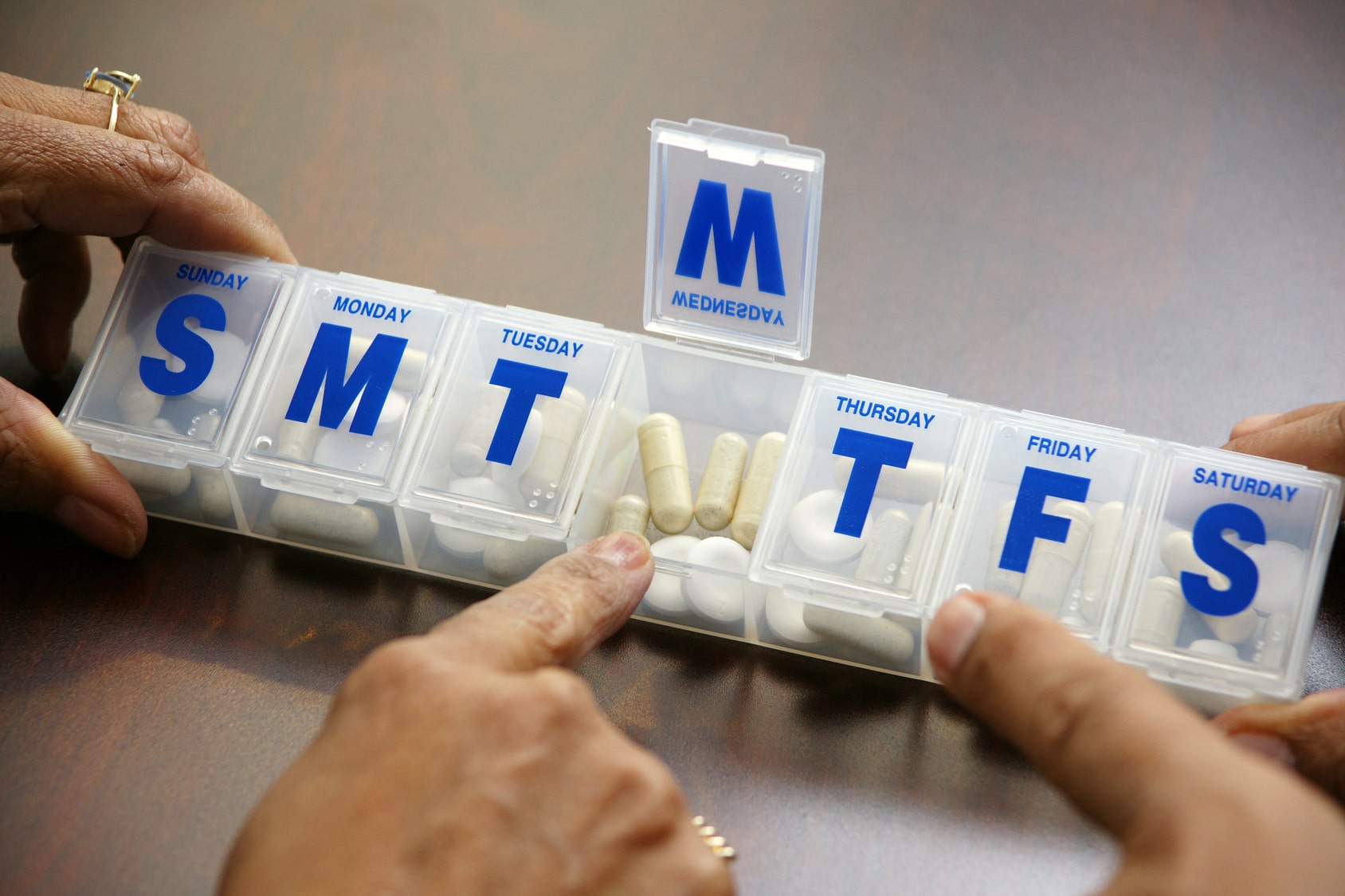 Elderly person opening pill box.