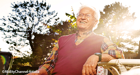 Older man laughing in the sunshine.