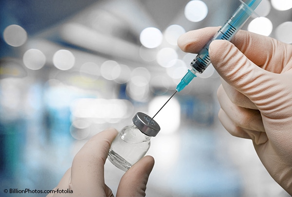 Scientist drawing vaccine from a vial.