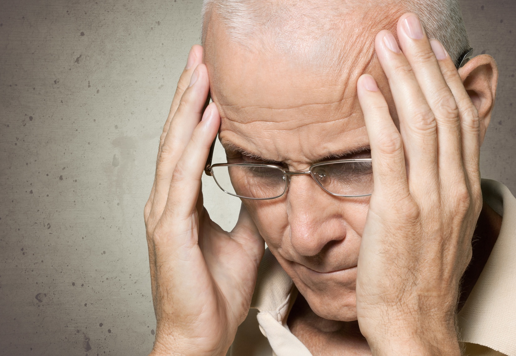 Elderly man holding his head.