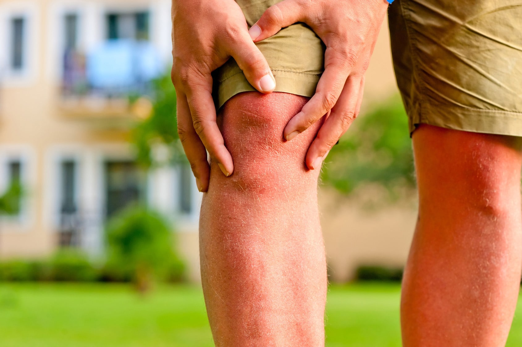 Person clutching their knee in pain.