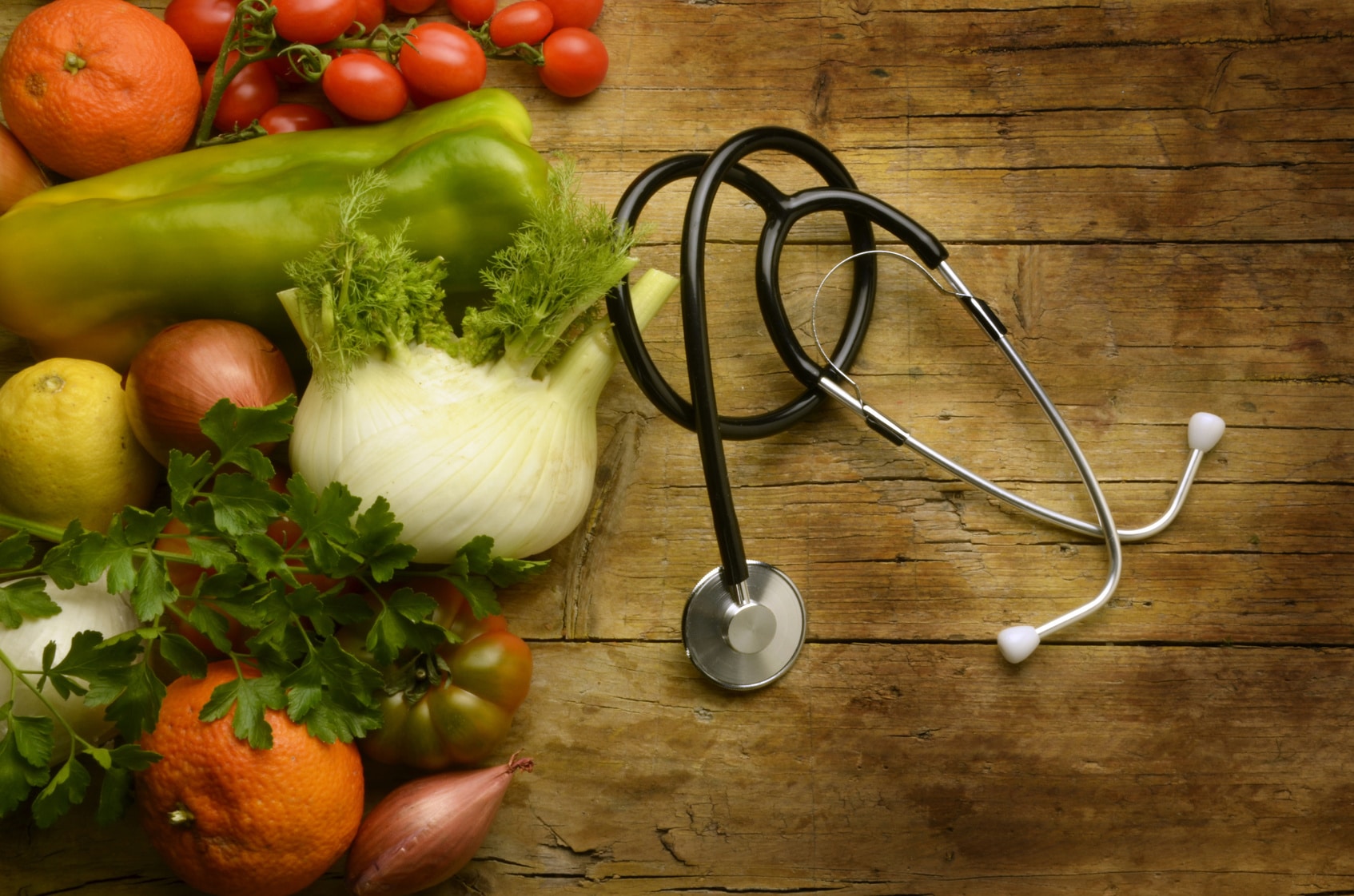 Stethoscope next to fruits and vegetables.