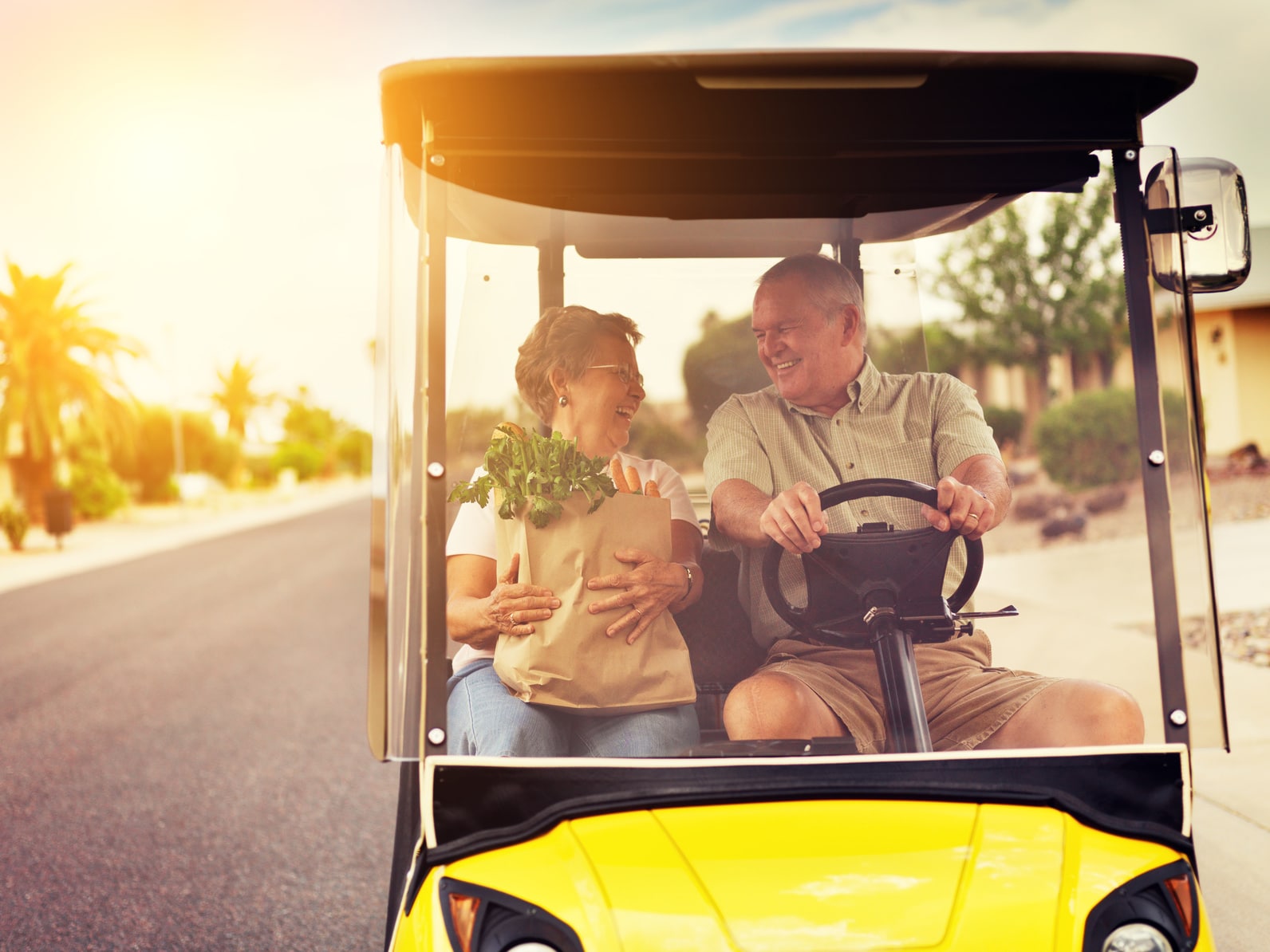 Older couple riding in golf cart.