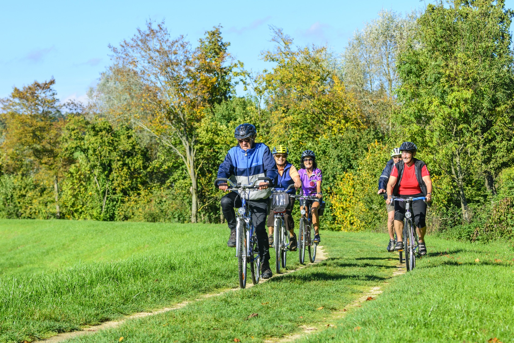 Seniors cyling on grassy trail.