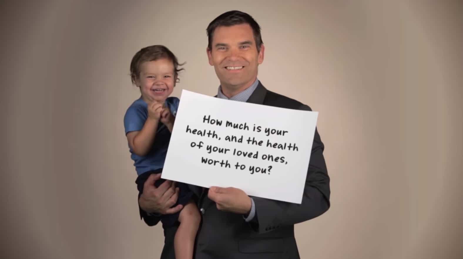 Man holding child and a sign for National Institutes of Hope video.