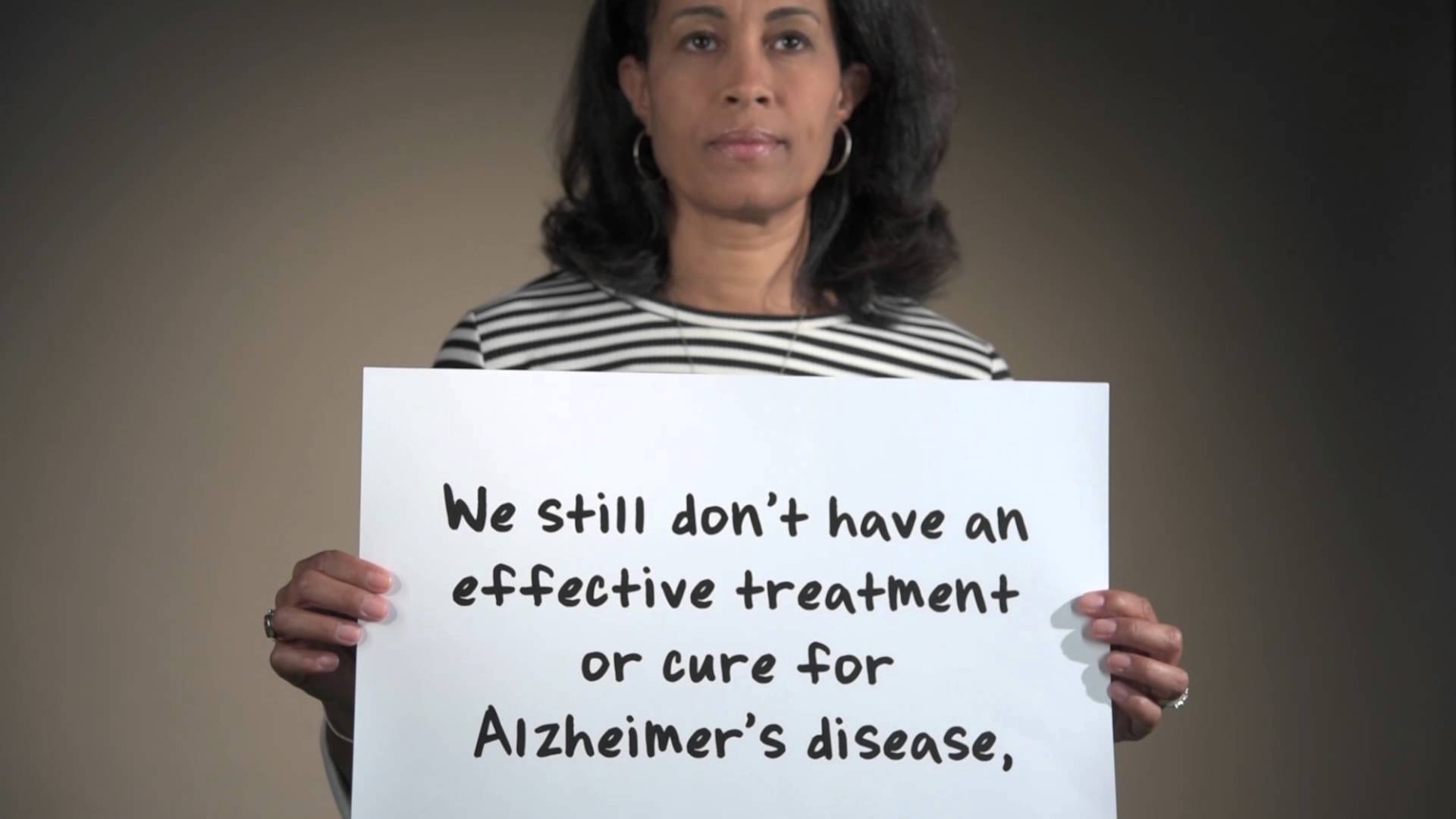 Woman holding sign on Alzheimer's for National Institutes of Hope video.