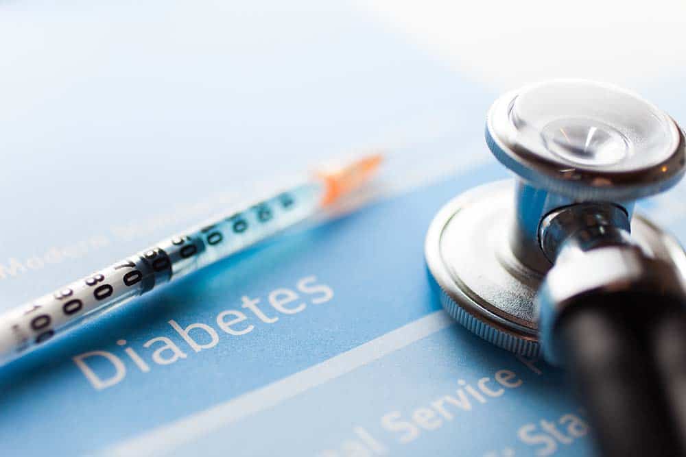 Stethoscope and insulin syringe lying on diabetes pamphlet.