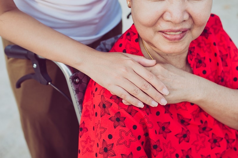 Young person pushing older woman in wheelchair.