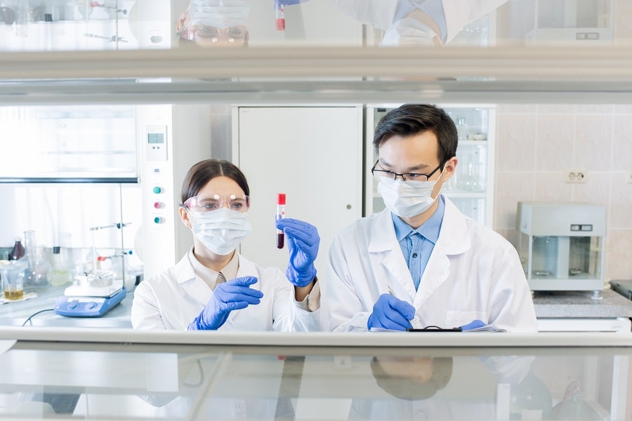 Lab technicians testing vial of blood.