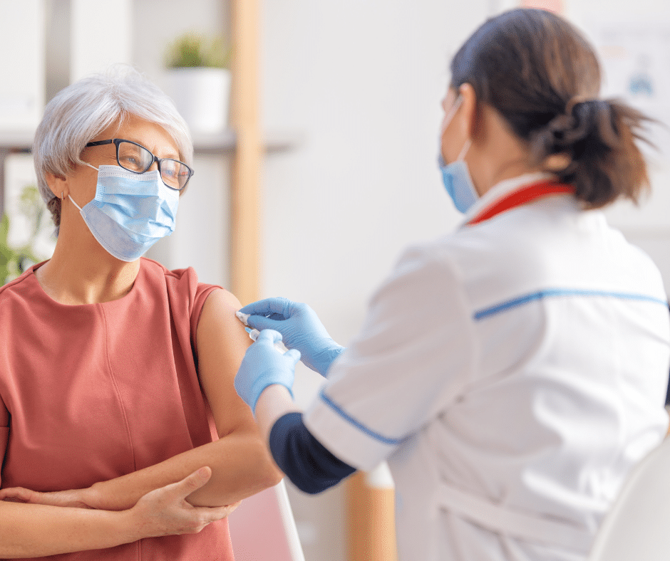 Health professional adminstering a vaccine to an elderly woman.