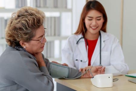 Doctor measuring senior woman's blood pressure.