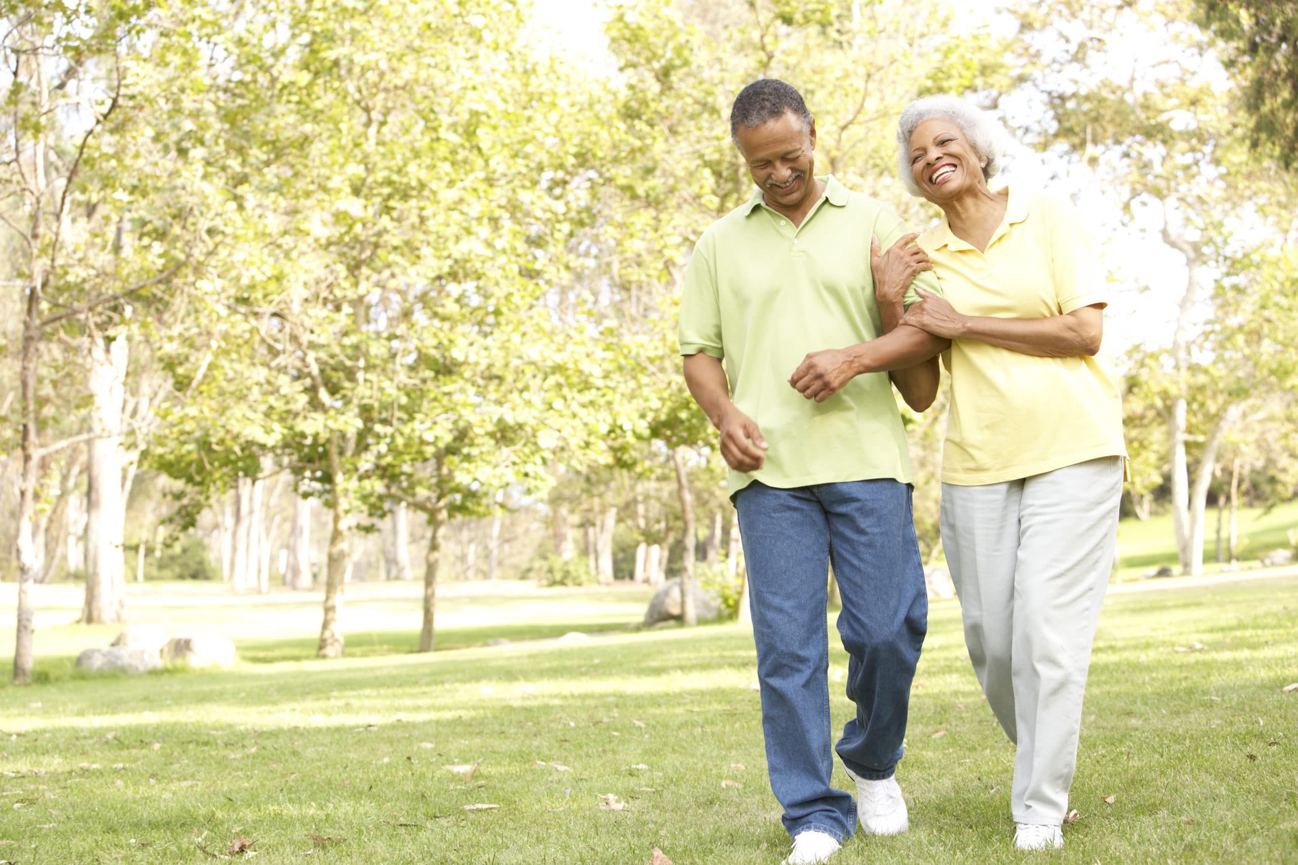 Elderly man and woman walking arm in arm outside.