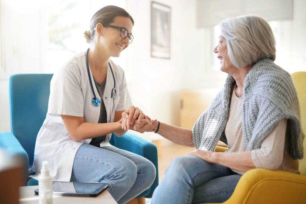 Nurse embracing patient's hands.`