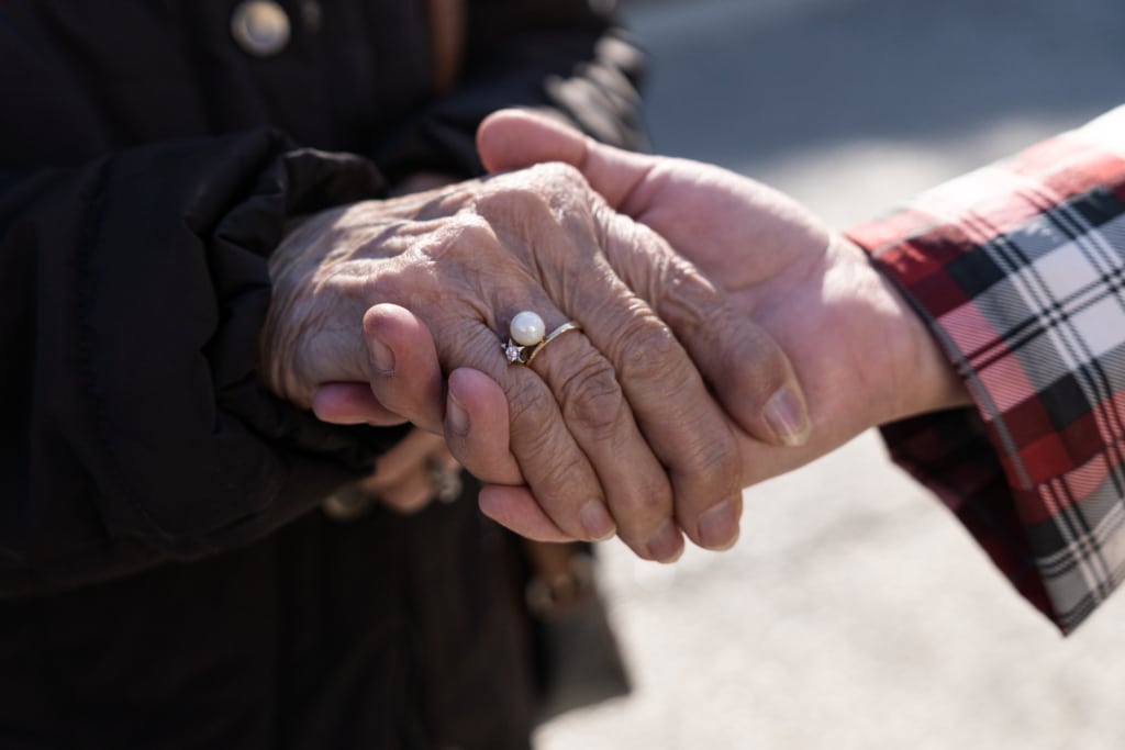 Older man's hand holding older woman's hand