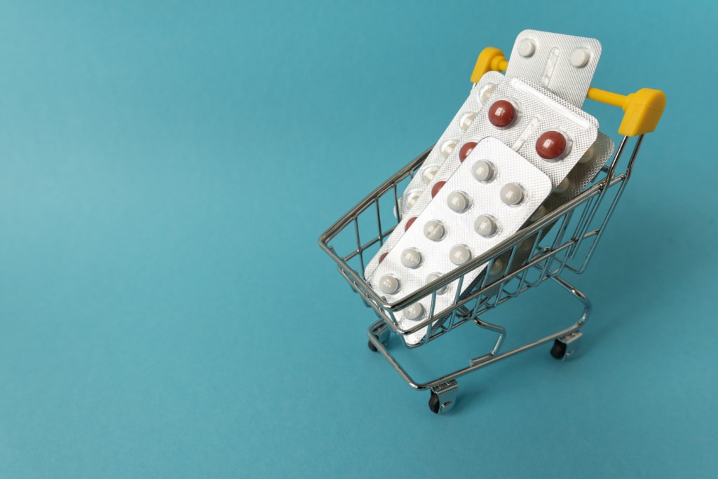 Miniature shopping cart filled with normal-sized prescription drugs
