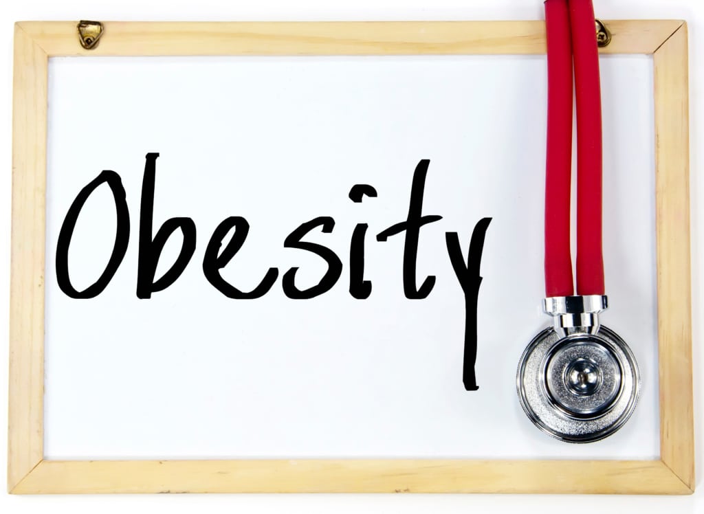 "Obesity" written in black marker on a dry-erase board draped with a stethoscope.