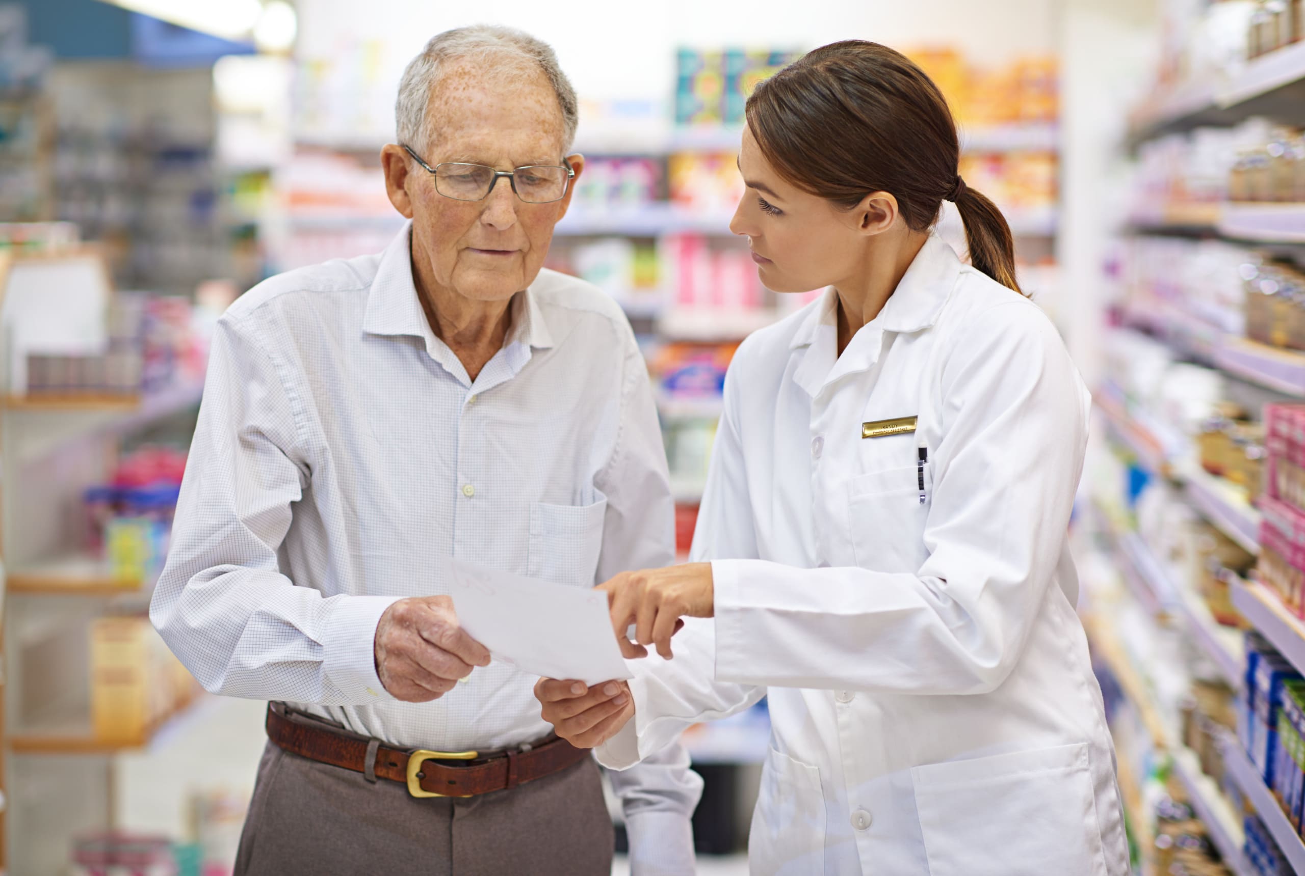 A young pharmacist helping an elderly customer with his prescription.