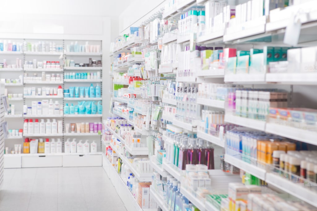 Medications and personal care items organized on drug store shelves.