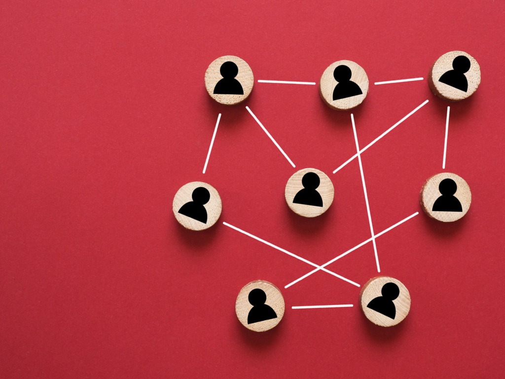 Schematic representative of teamwork. Wooden discs with people symbols connected by white lines.