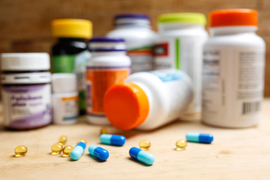 Several pill bottles with several capsules in the foreground.