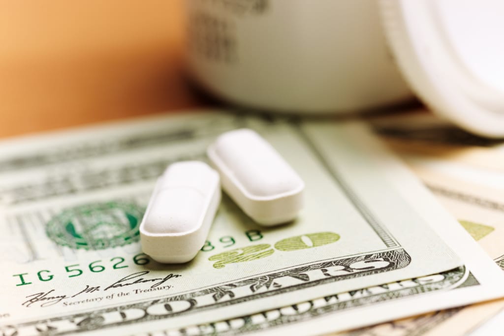 Two oblong white pills sitting on top of some American currency.