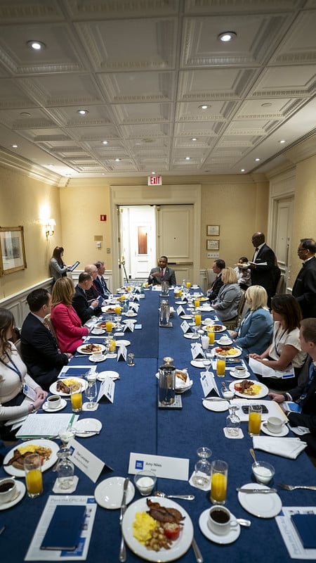Rep. Don Davis (R-NC) at the helm of a long table of professionals eating breakfast and engaged in discussion.