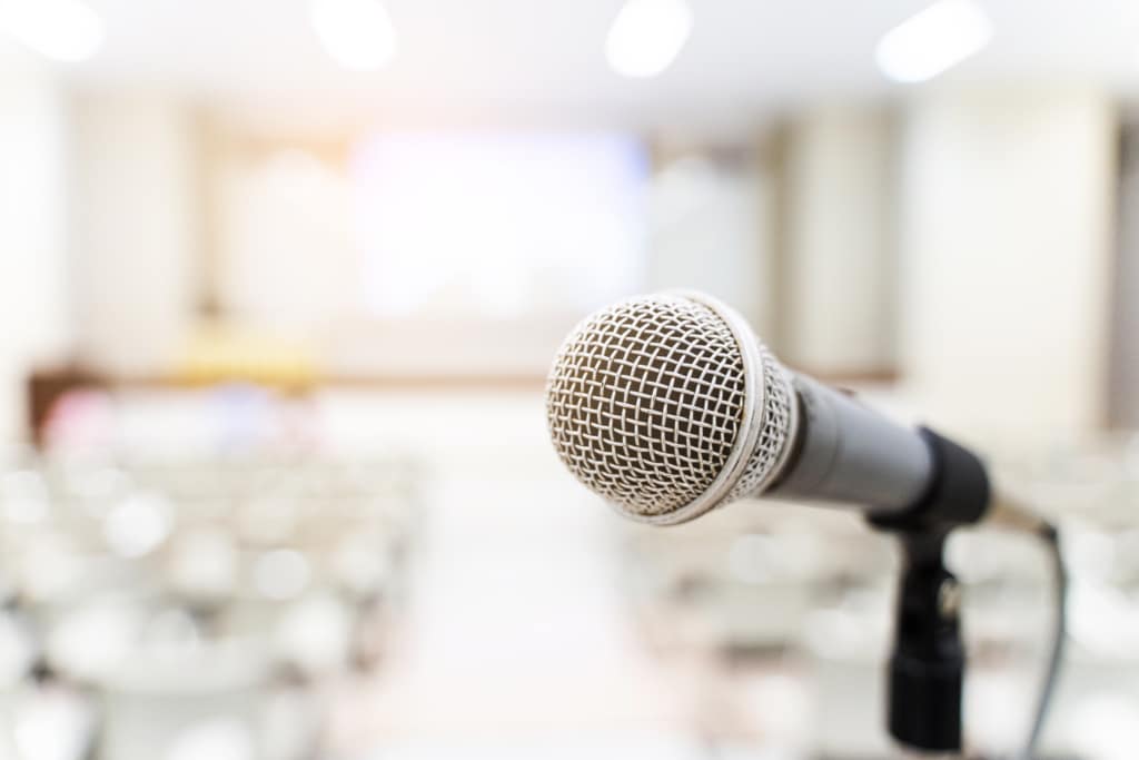Microphone in foreground of blurred auditorium