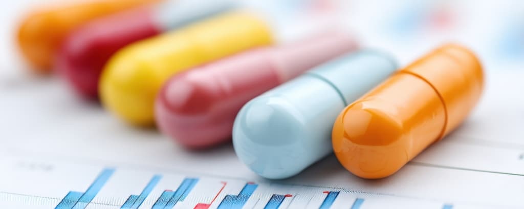 Close-up of colorful pill capsules on printed bar charts