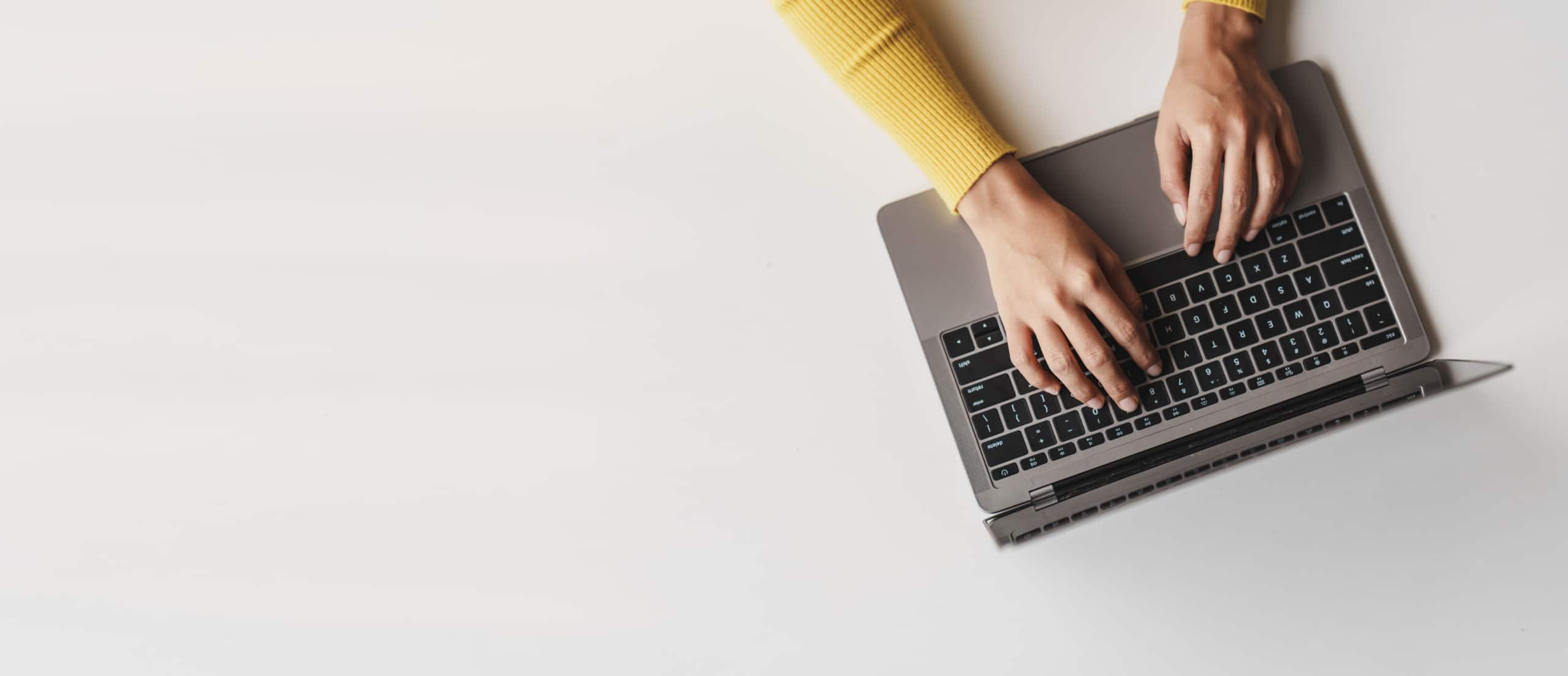 Birds-eye view of a person typing on a laptop keyboard.