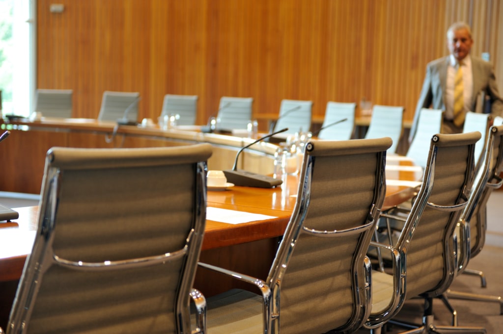 Empty professional chairs around a circular board room table.