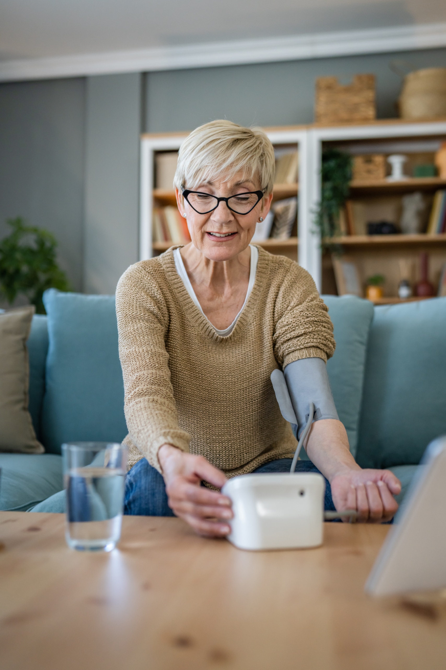One woman senior caucasian female use blood pressure device on hand to check health results while sit at home real people health care concept