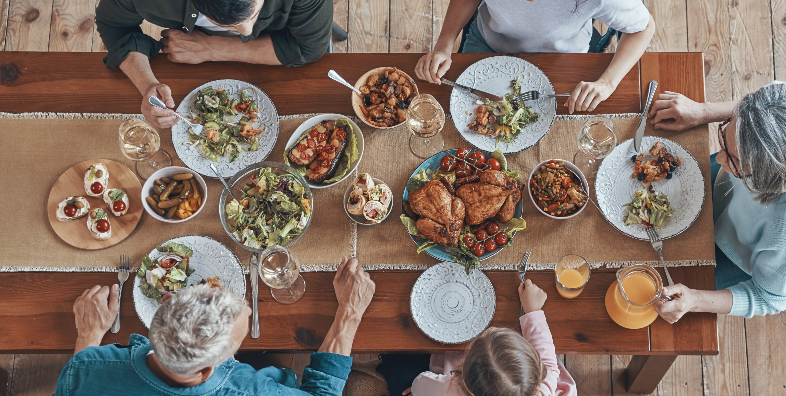 Birds-eye view above a thanksgiving dining room table with people gathered around.