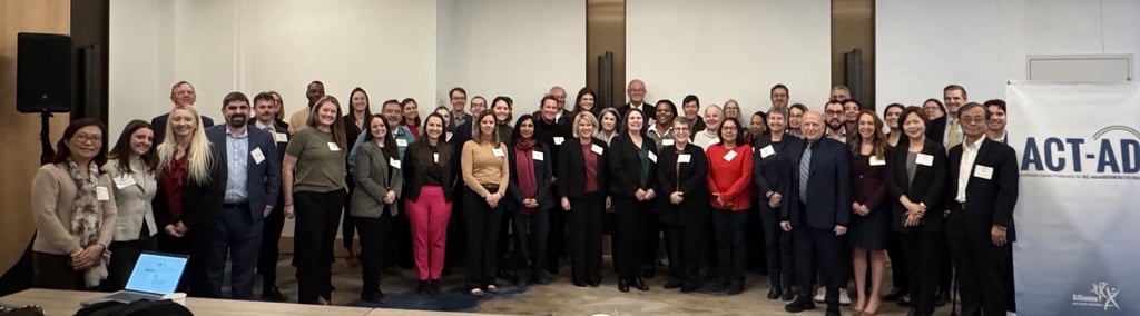 Large group of professionals gathered next to ACT-AD sign.