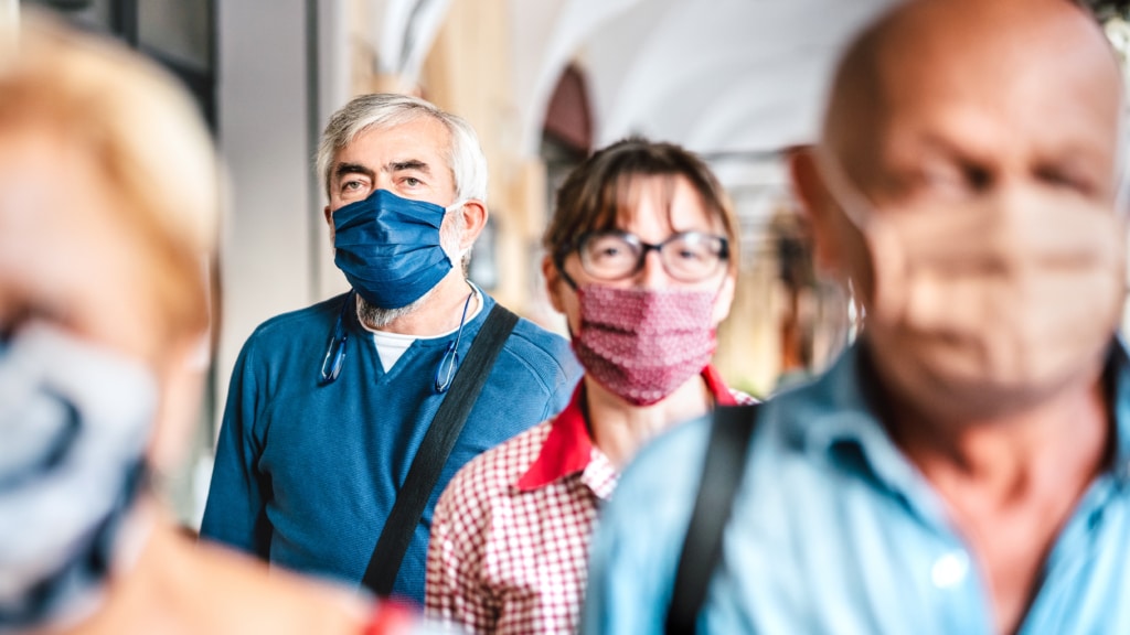 Several older adults walking on a street wearing homemade masks to prevent illness.
